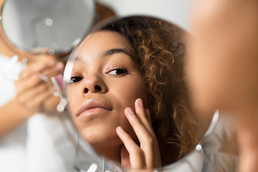 Woman looking at her face in a mirror